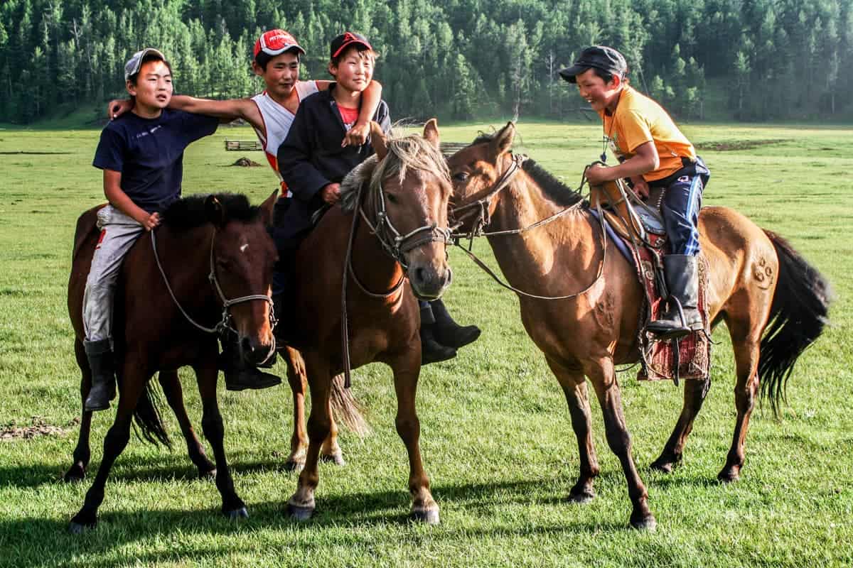 Young Mongolian men riding horses in rural Mongolia