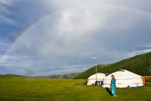 A rainbow arches over two white tents of Mongolian Gers in rural Mongolia