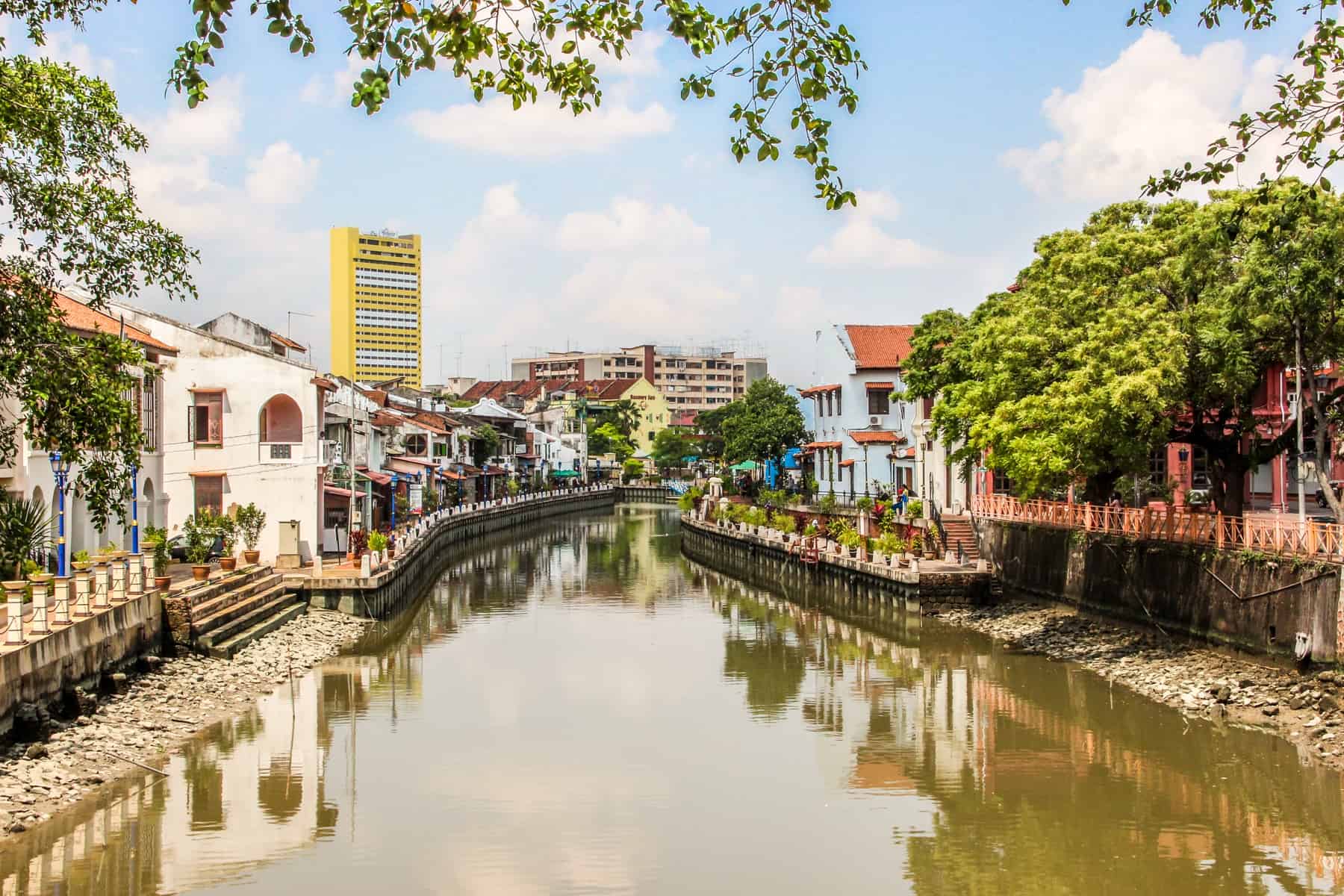 A view of the river in Melaka, Malaysia lined on either side with colonial style houses and trees