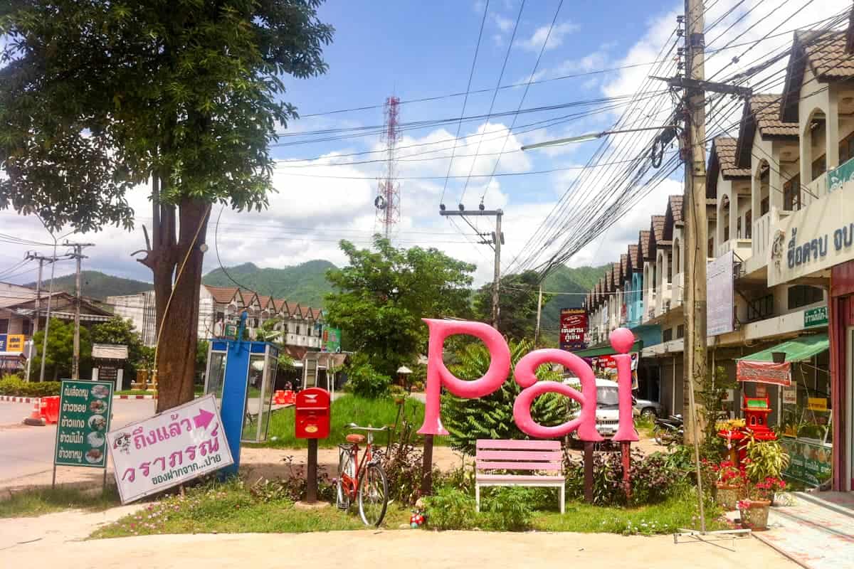 A pink Pai sign which stands on a road town in the city as a welcome for visitors