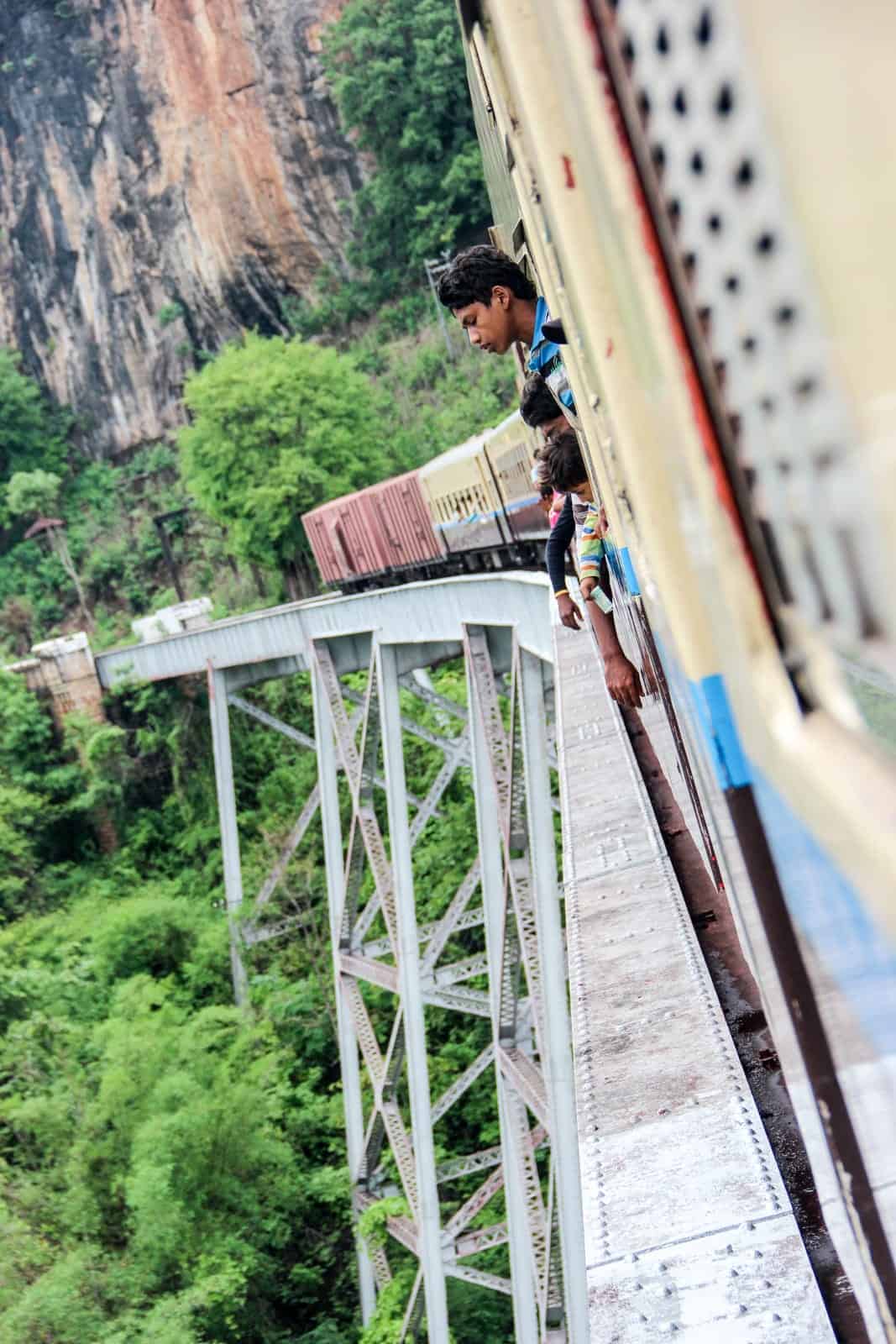 A man looking out and down from the train window while crossing the Goteik Viaduct in Myanmar 