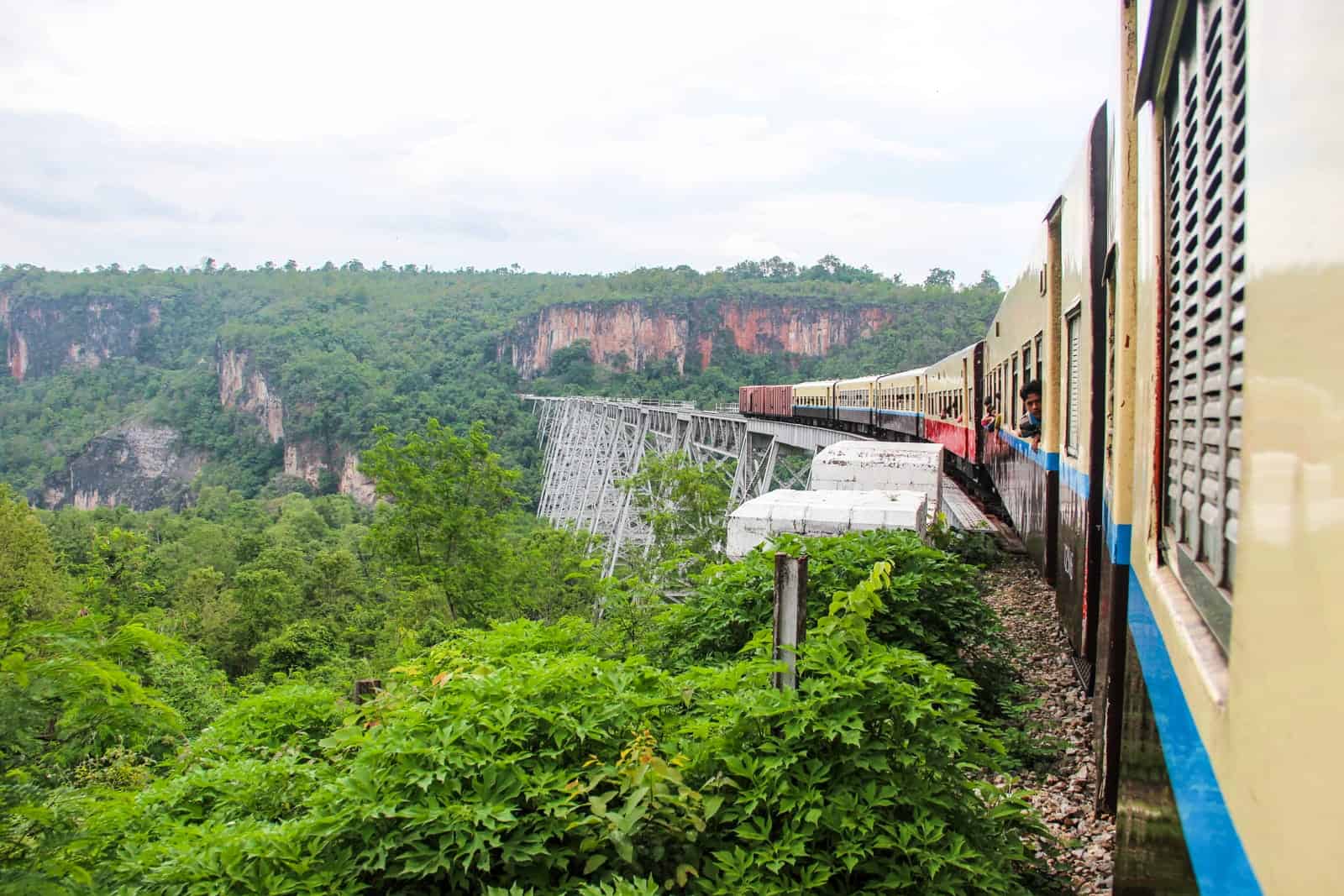 Riding the beige and blue train across the silver Goteik Viaduct bridge in Myanmar.