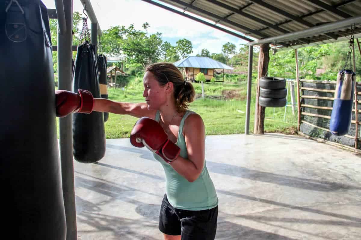 Woman in exhasuting Muay Thai training in Thailand, practicing punching 