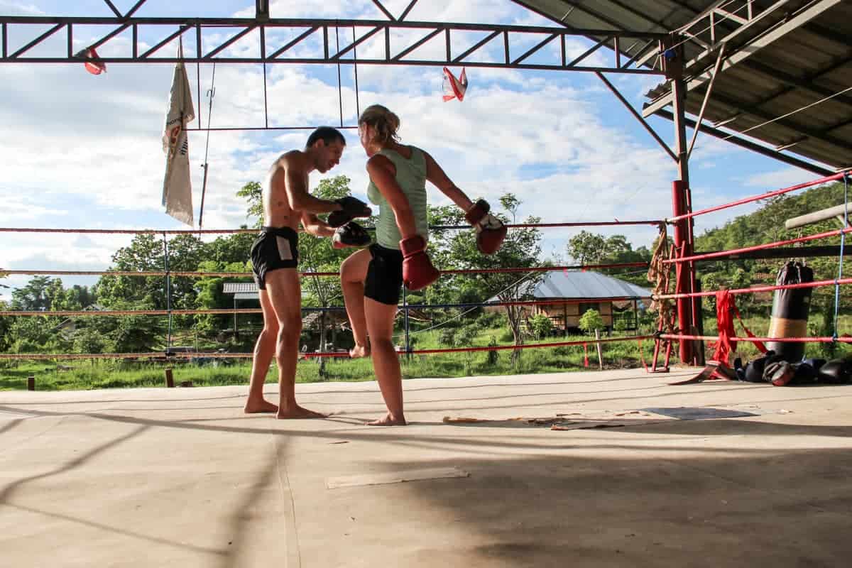 Woman trains with a Muay Thai instructor in a boxing gym in Thailand