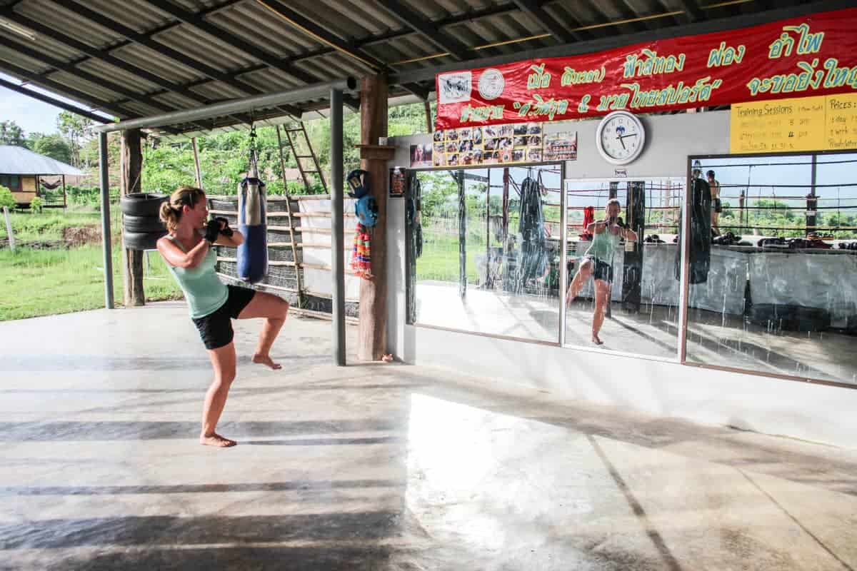 Woman practicing high kicks in front of a mirror during a Muay Thai training in Thailand 