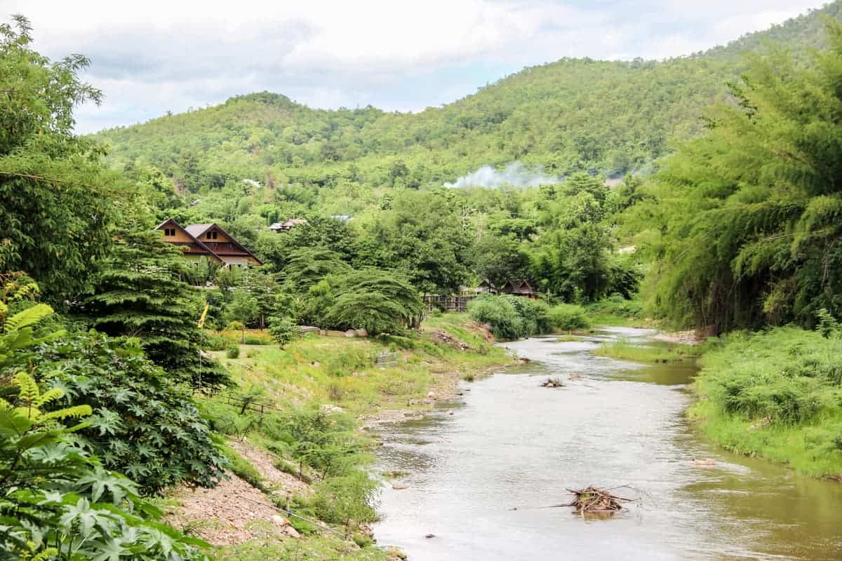 El viaje de la ciudad de Chiang Mai a Pai te lleva a densos valles verdes con un río bajo y refugios de madera apartada.