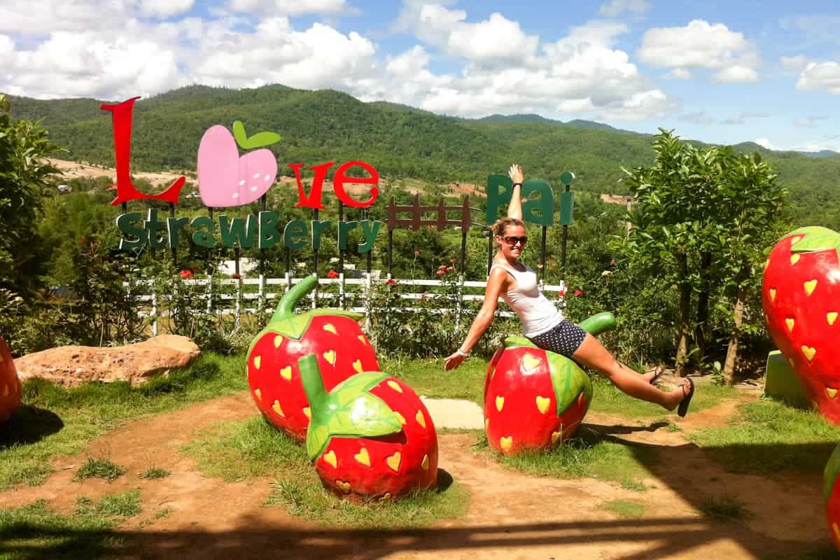 Woman posing on giant Strawberry structures at the Strawberry Cafe in Pai, Thailand