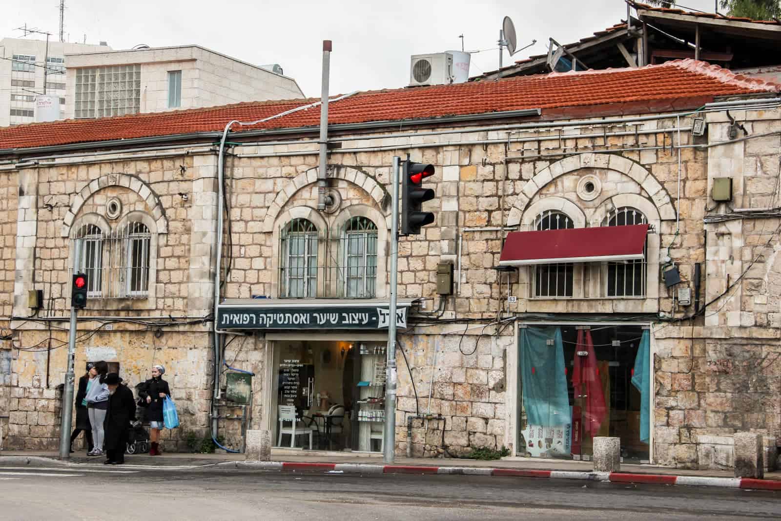 A honey coloured stone building, with terracota roof tiles and a open store front on Jaffa Road in Jerusalem city