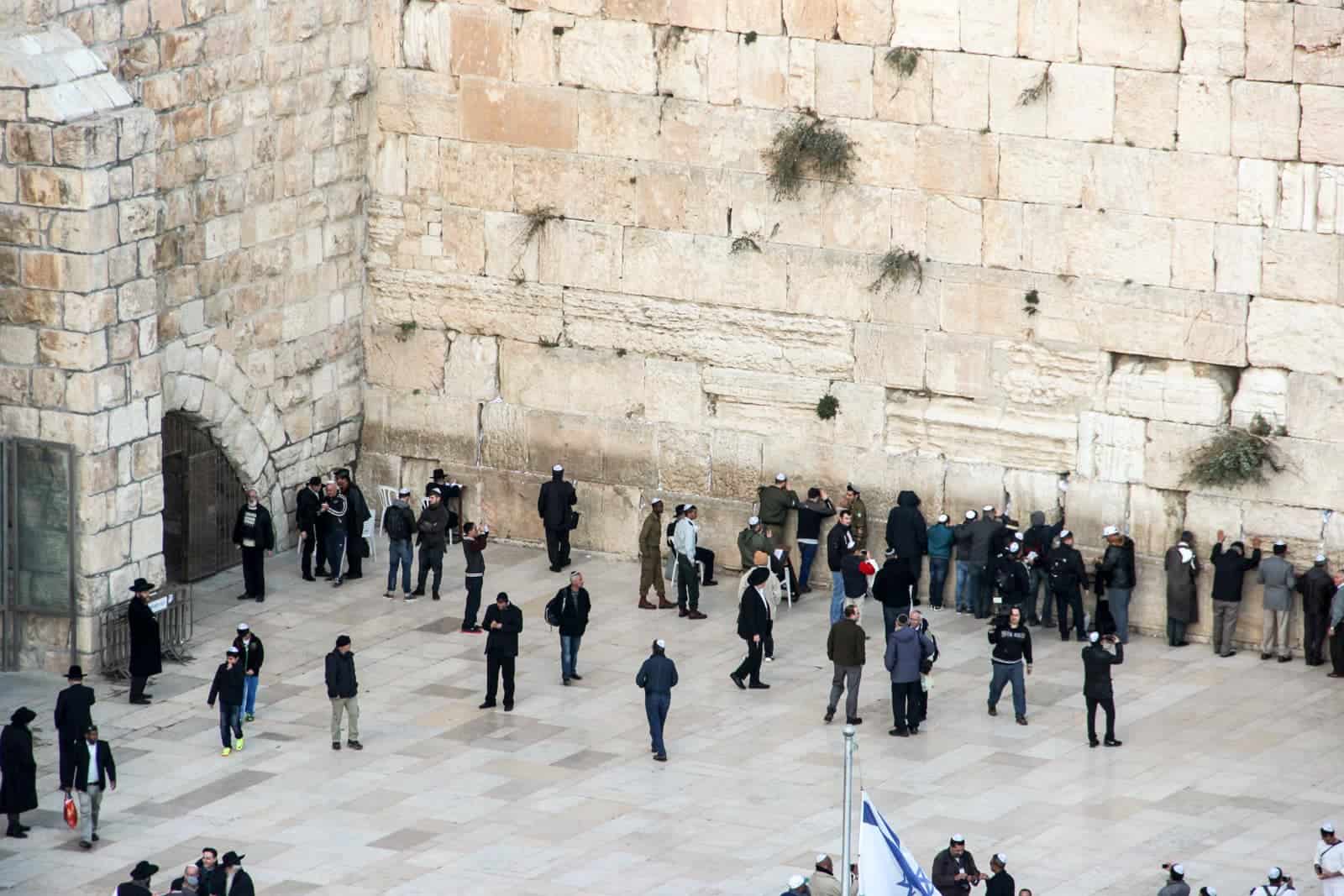 A large group of Jewish men dressed in black prayed against the the golden stone Western Wall in Jerusalem, Israel