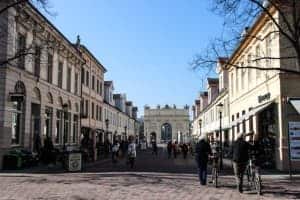 A street in potsdam lined on both sides with tall white and cream buildings. At the end of the street, and in the middle is a white arch structure.