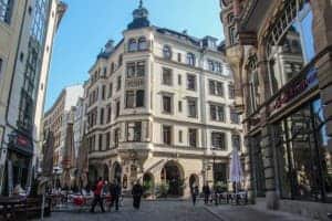 A huge, classic looking white building on a street in Leipzig city in Germany. Either side of it are two modern, glass-fronted structures.