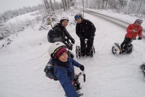 A woman and two men look into the camera while riding Segways in the snow in Tirol, Austria