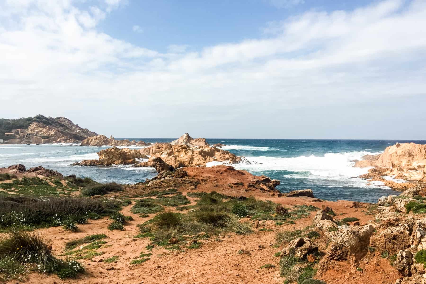 Crashing waves break on the golden rocky coastline of Menorca, Spain.