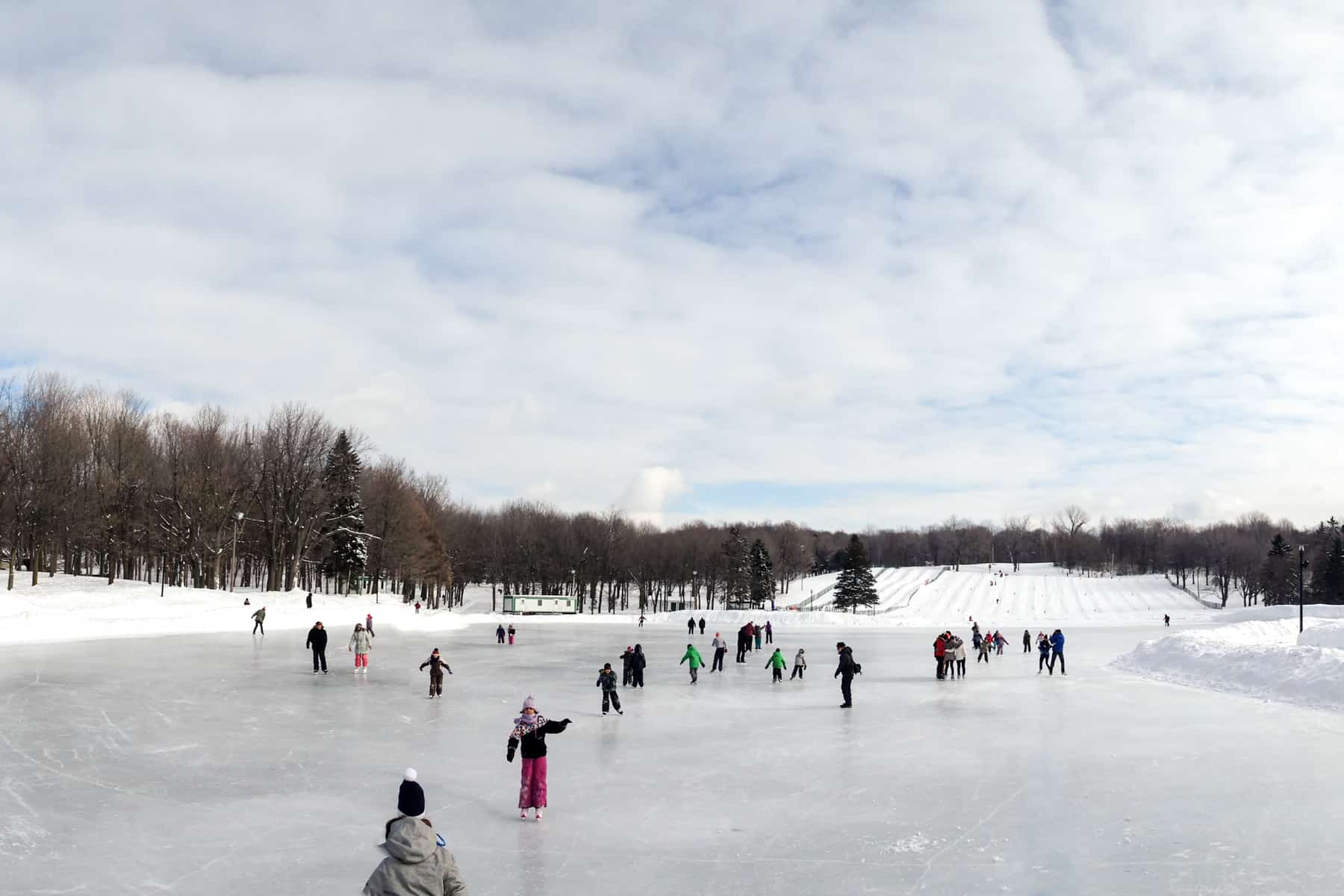 People ice skating on a frozen lake of Mont Royal in Montreal in winter. 