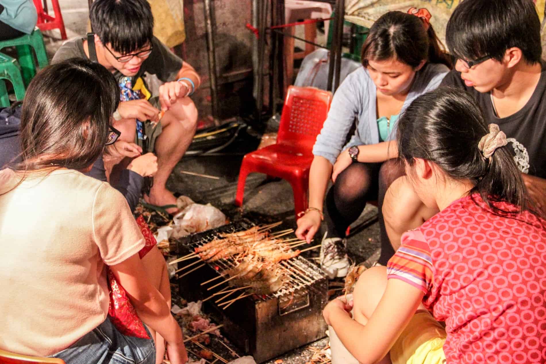 A group of friends grill meat on a BBQ at a Night Market in Tainan. 