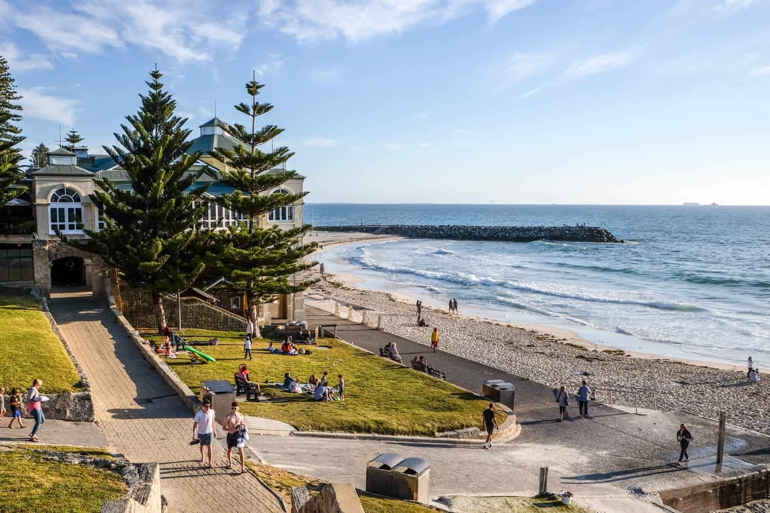 Pathways and trees run parallel to the sandy shores and blue waters of Cottesloe Beach in Perth