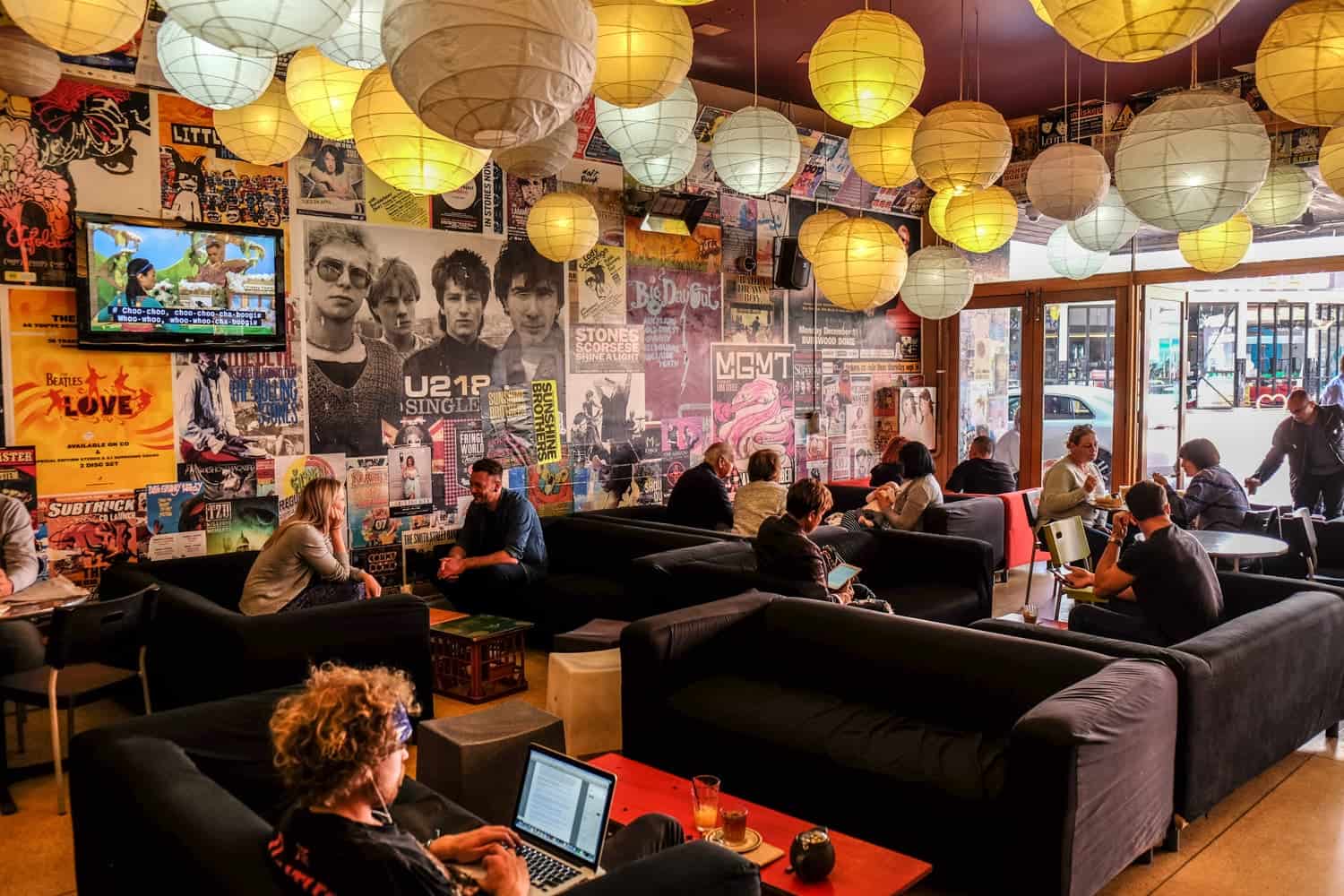 A cafe in Perth whose walls are lined with music gig posters with paper lanterns hanging from the ceiling