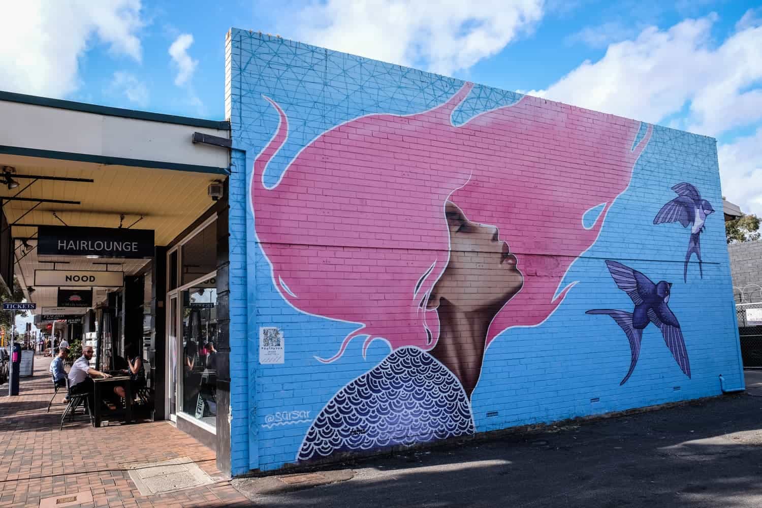 Street art of a woman with pink hair on the side of a building in Leederville, Perth