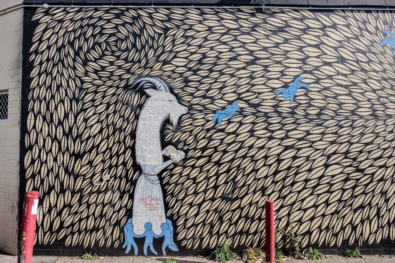 Arte callejero de una cabra con pequeñas figuras humanas azules en Leederville, Perth