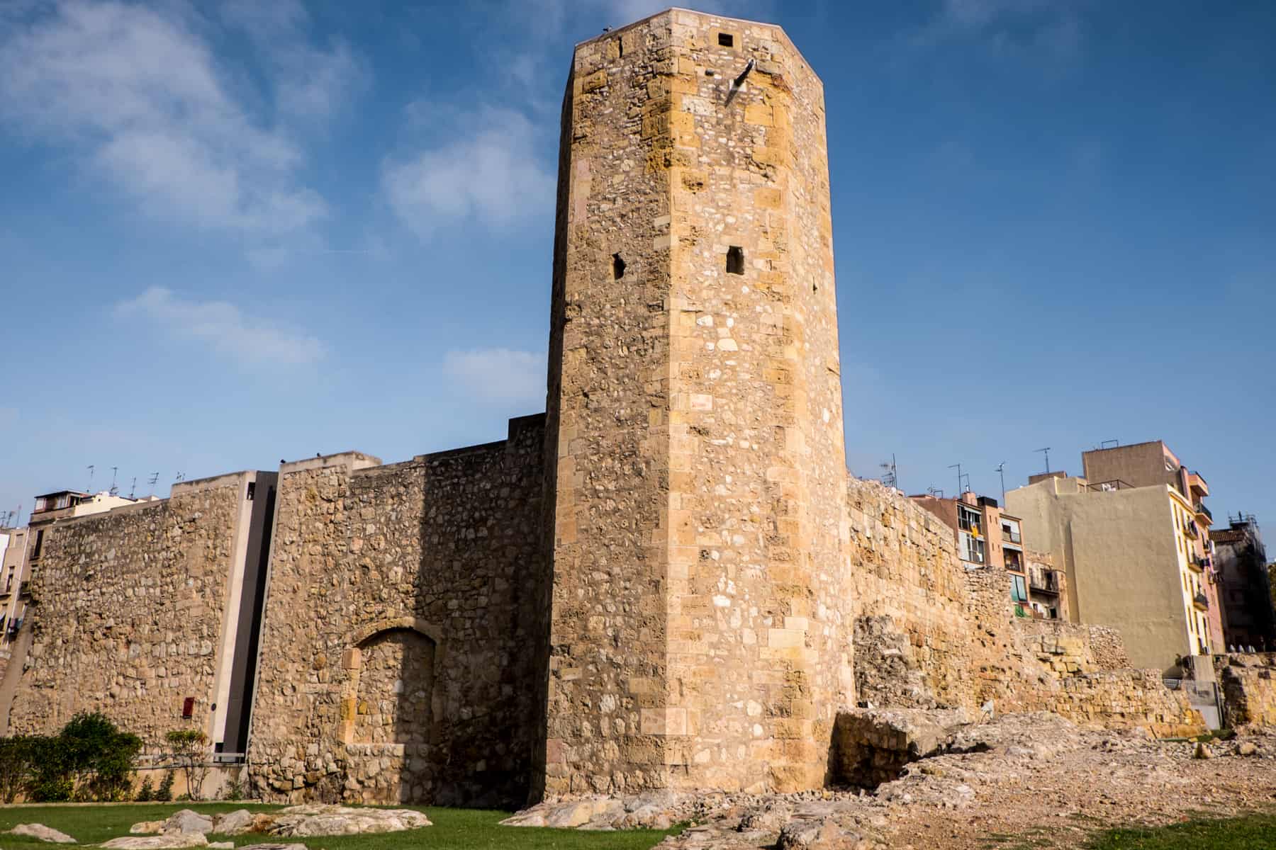 The bold golden stone wall and column structure of the Roman Circus and Praetorian Tower in Tarragona Spain, against a blue sky