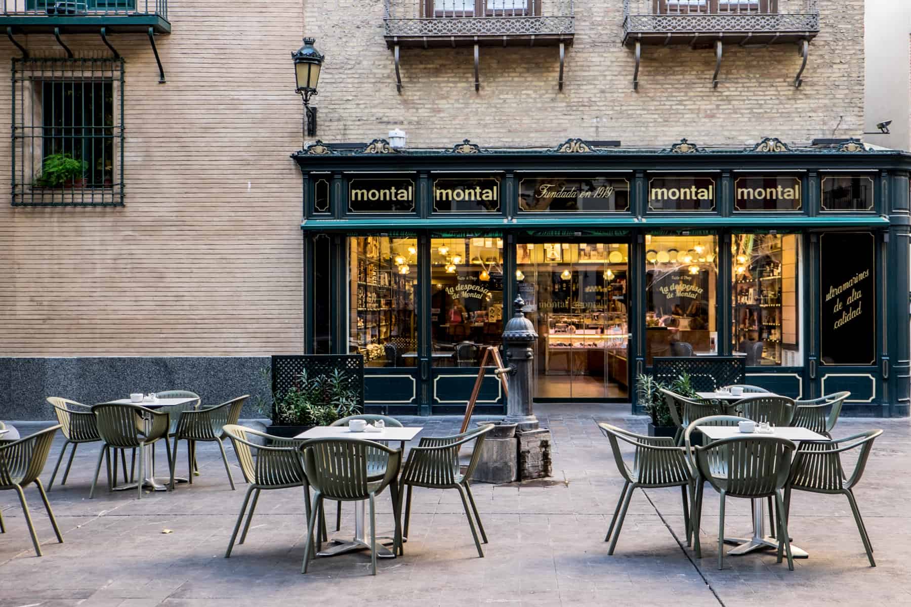Empty tables and chairs outside a black panelled restaurant exterior which lists the word "montal" four times.