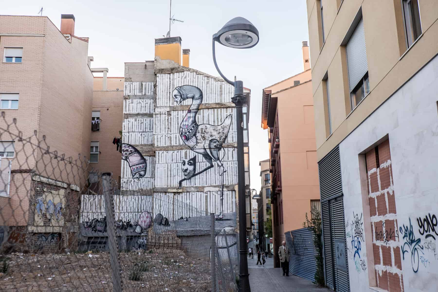 A crumbling building next to a yard of rubble is covered is lines of white paint and a bird-like mural - bringing life to a run down street in local Zaragoza.