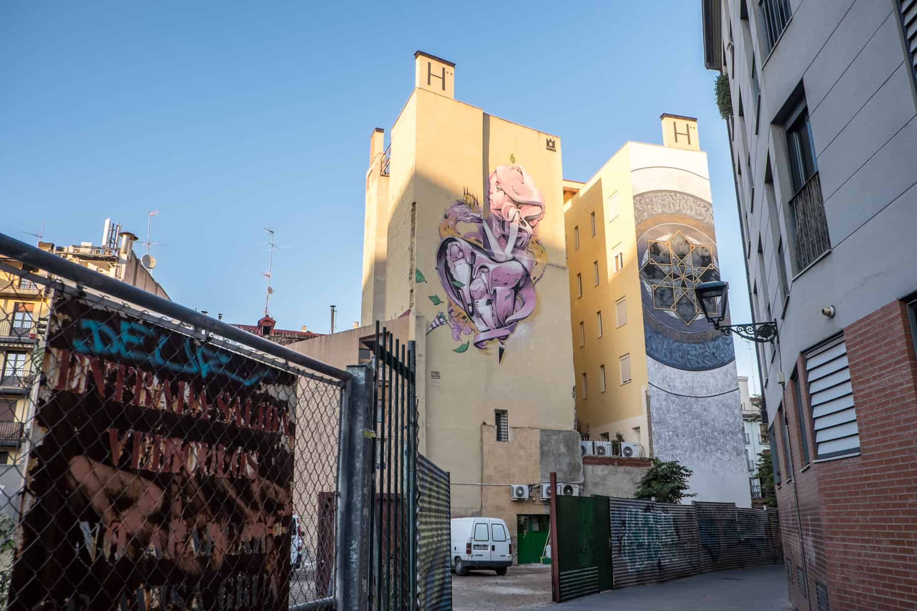 Detailed artworks on two, tall yellow apartment blocks in Zaragoza's outer city neighbourhoods. 