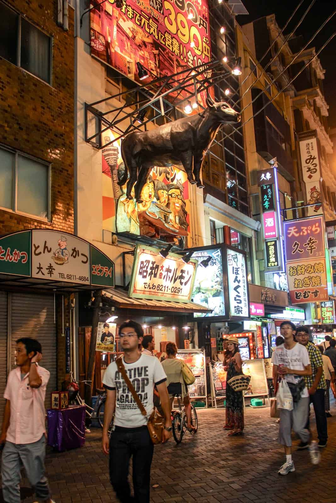 A model of a bull hangs outside a street food outlet on a busy Osaka street to denote the type of food being served. 