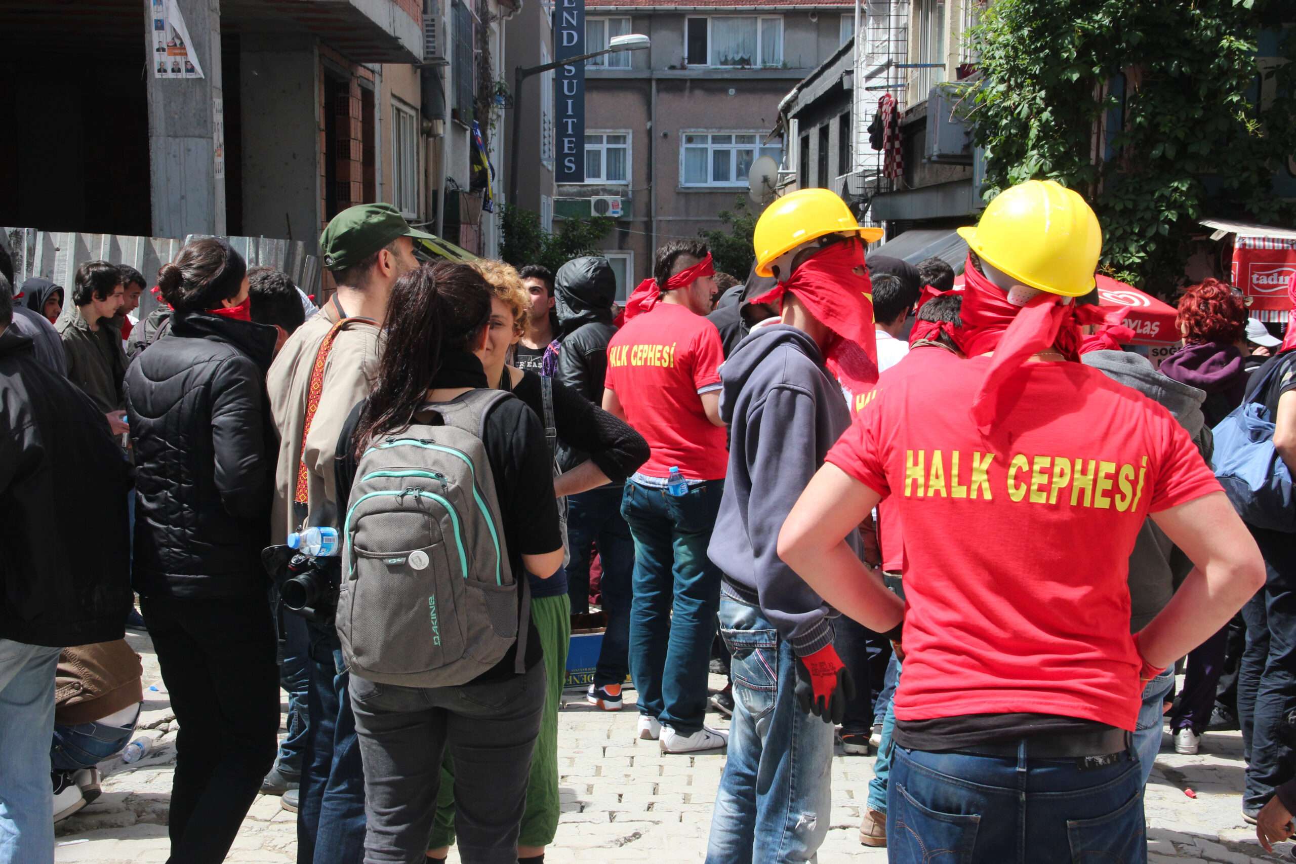 A group of protesters, some in red t-shirts and yellow helmets, gathered together in a street in Istanbul.