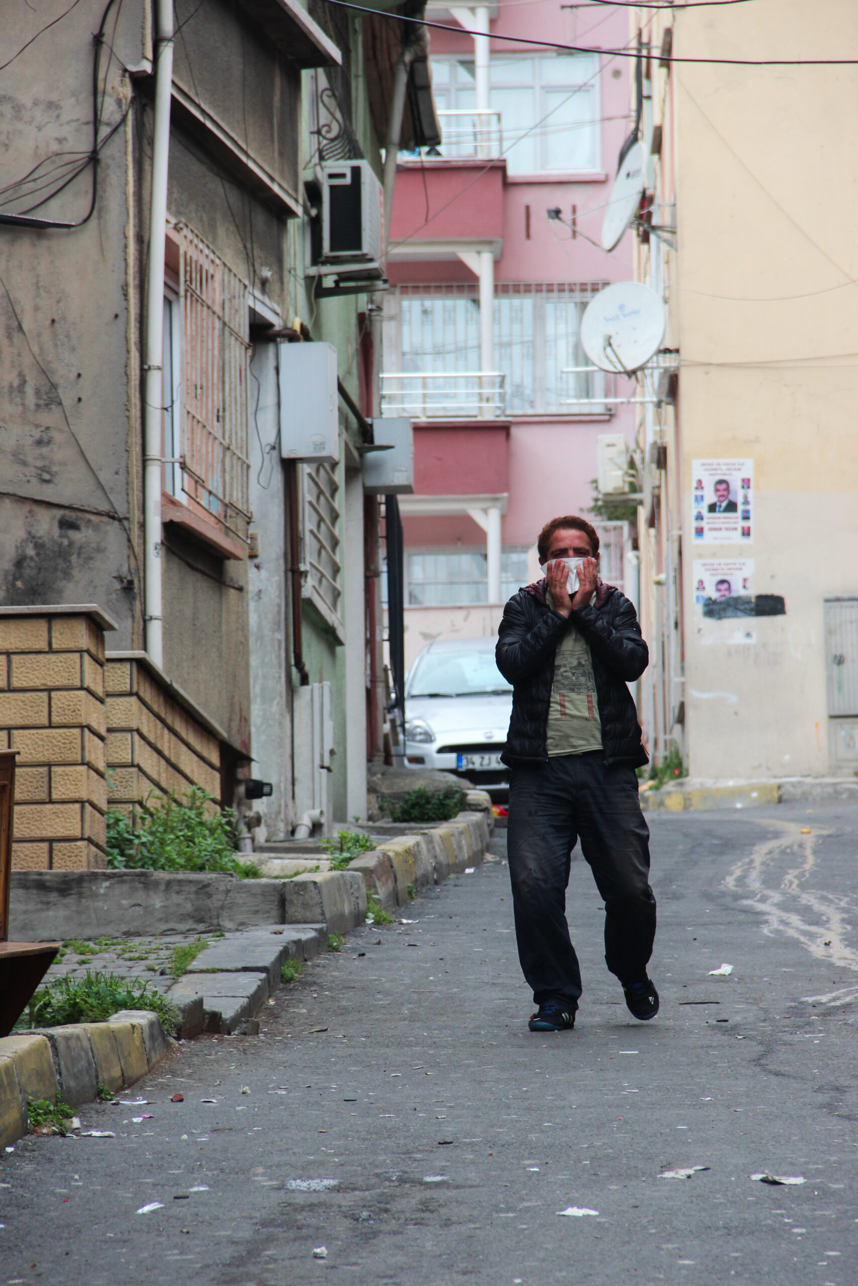 A man walking down a street in Taksim, Istanbul during the May Day riots, covering his face to protect from the tear gas in the air.