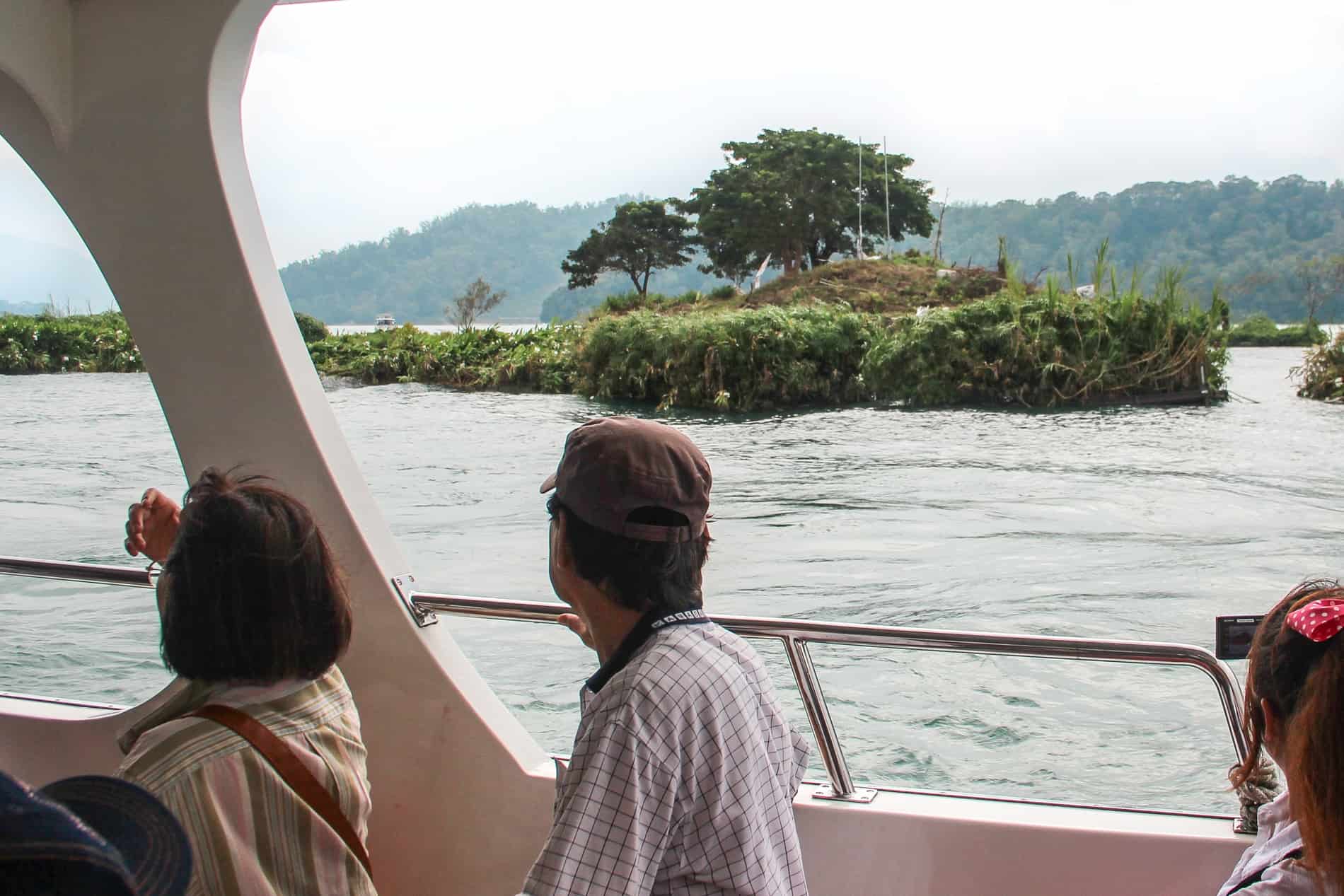Two people on a boat looking out to small islands on Sun Moon Lake, Taiwan. 