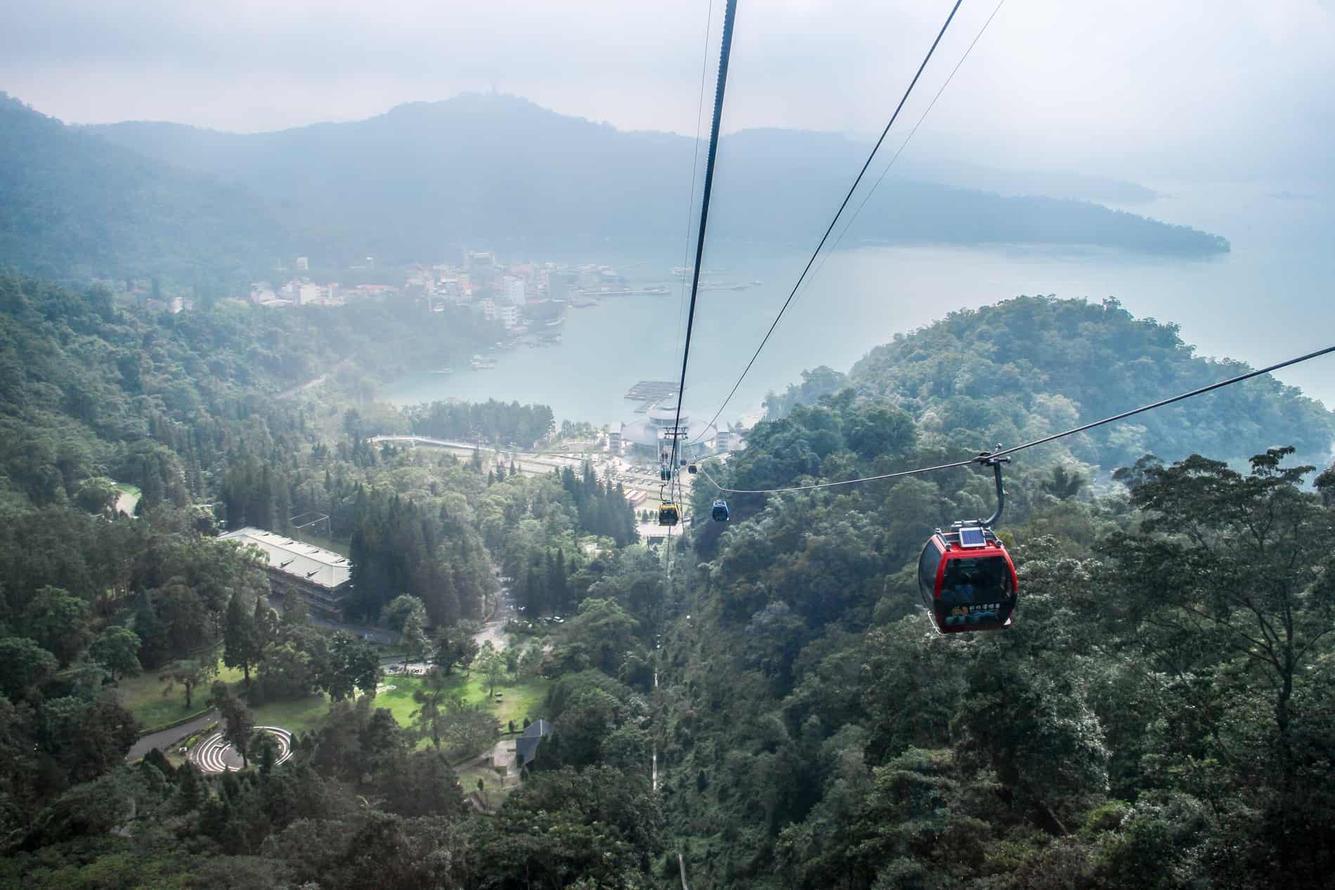 Ropeway gondola cars rising above the forested islands surrounding Sun Moon Lake, Taiwan.