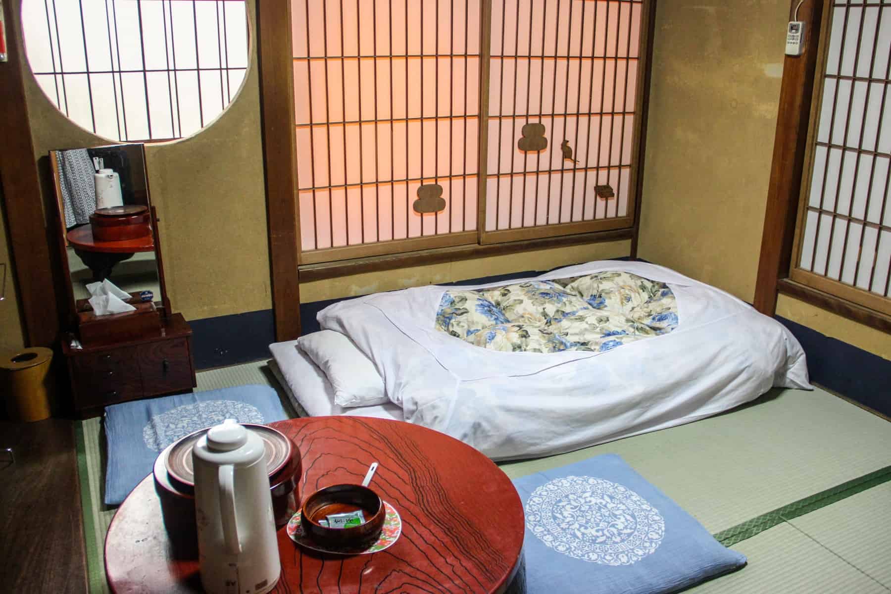 The wooden interior, tea table and white futon in a Japanese Ryokan in Tokyo.