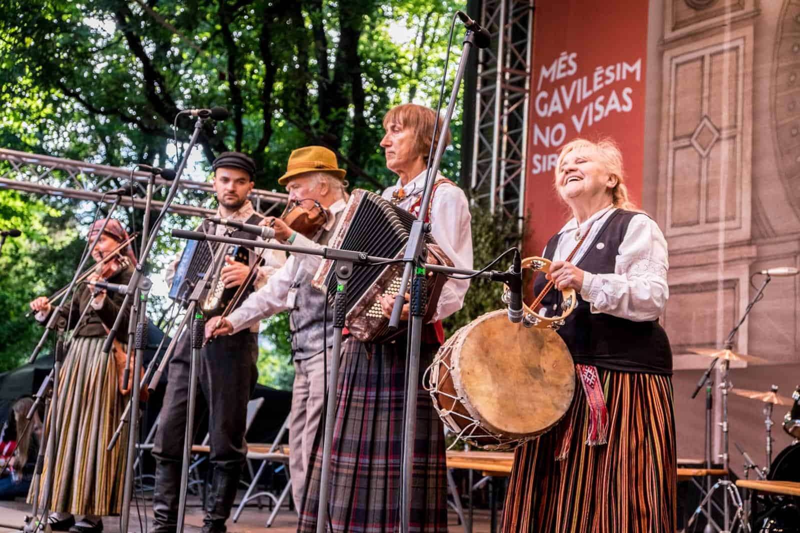 Four man band performs on stage in a Riga Park for the Song and Dance Celebration in Latvia