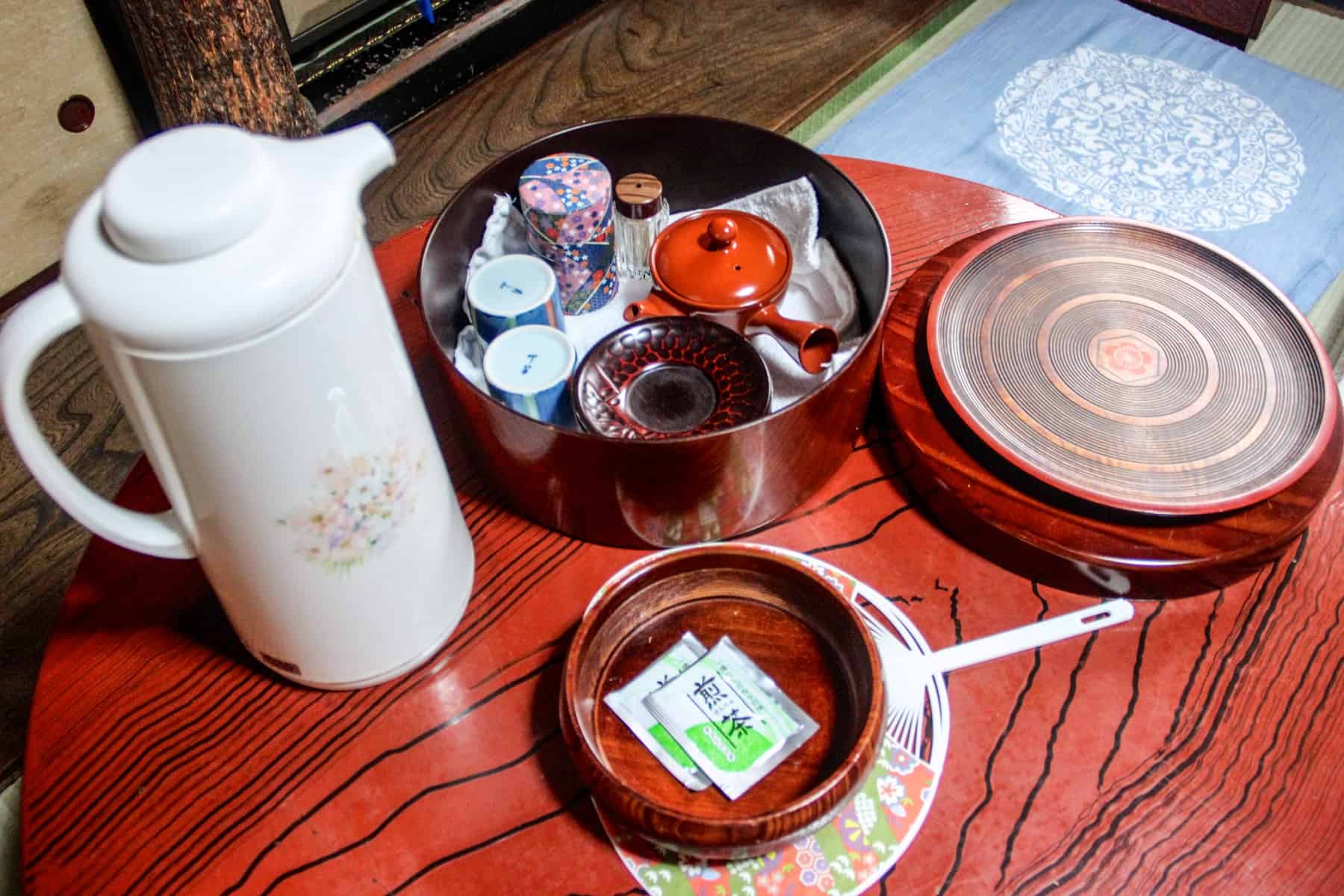 A Japanese tea set and white flask on a wooden table in a traditional Ryokan accommodation. 