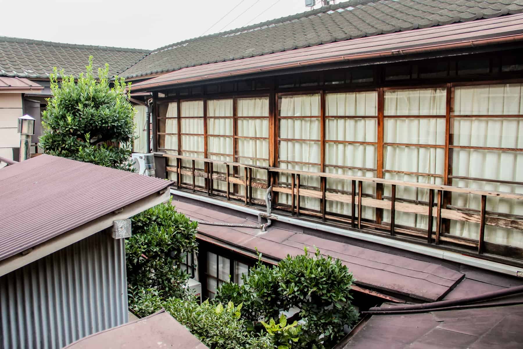 The large wooden windows and balconies on the exterior of a Japanese Ryokan in Tokyo.