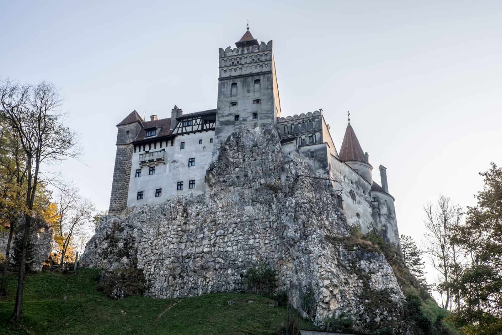 The silvery stone fortress exterior of Bran Castle in Transylvania, Romania, surrounded by woodland