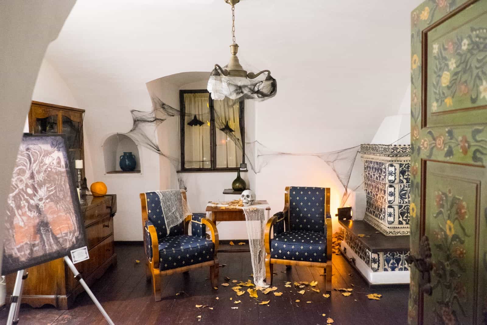 Two old chairs, draws and a green cupboard inside Bran Castle, Transylvania, Romania, decorated in Halloween spiderwebs, skulls and pumpkin