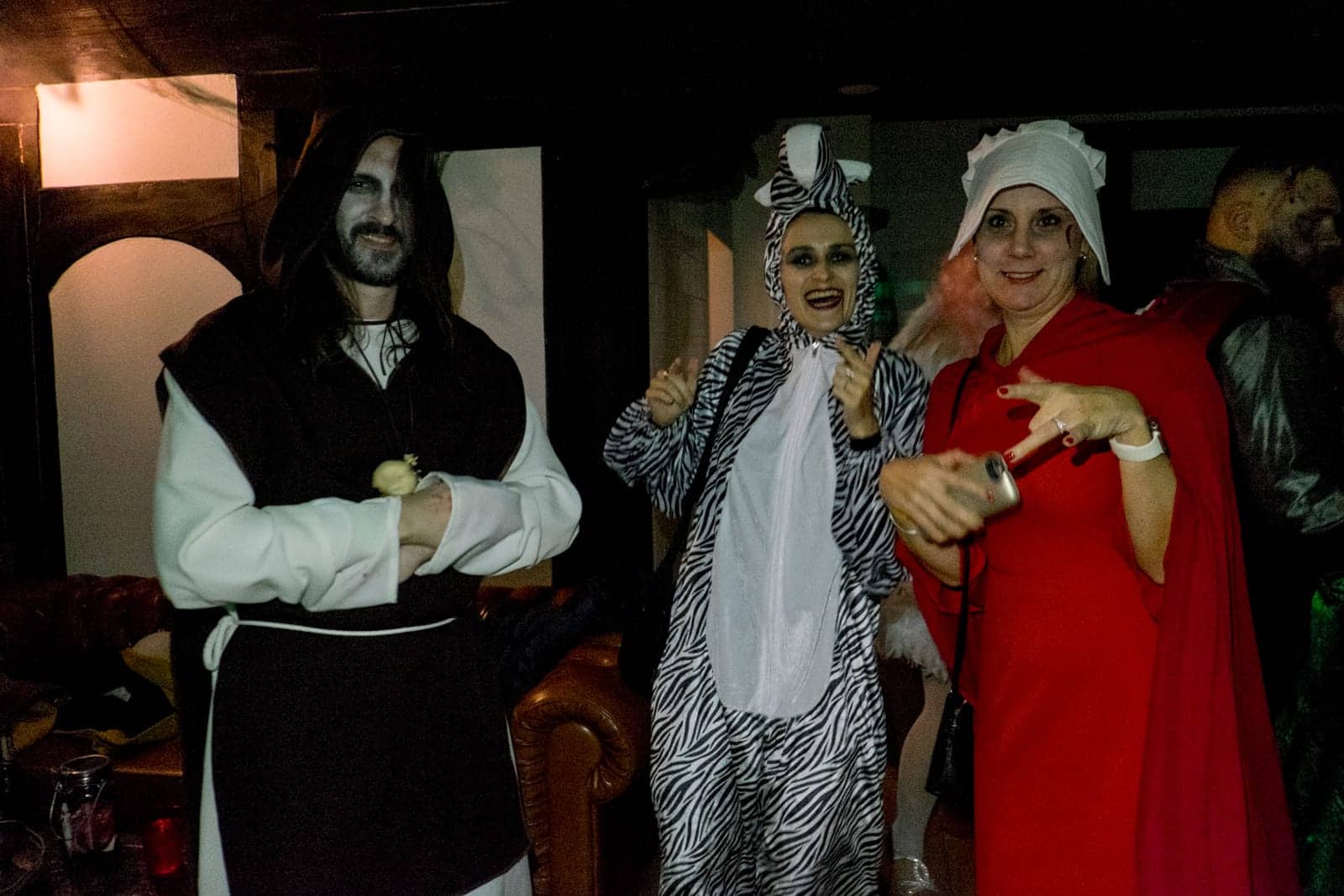 A man dressed as a monk, a women dressed as a zebra and another as a handmaid pose at a Halloween party in Bran Castle, Transylvania, Romania