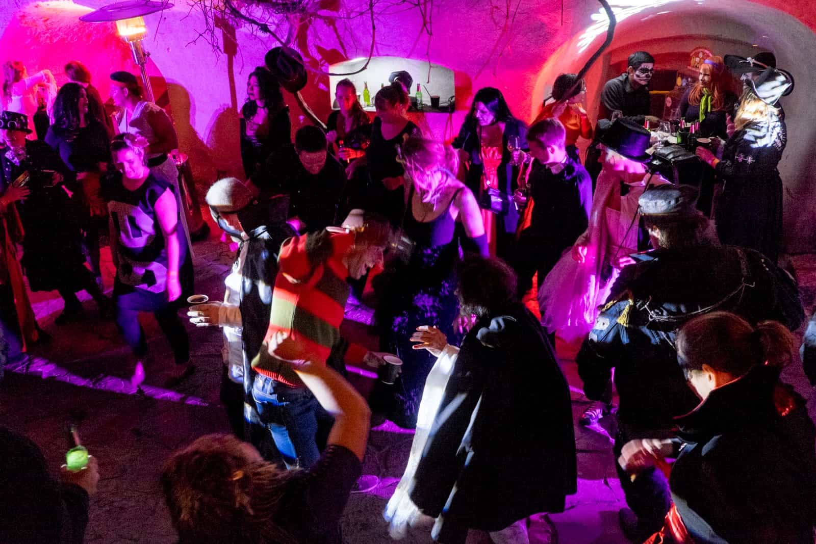 A group of people in Halloween fancy dress party inside the ground of Bran Castle in Transylvania, Romania. The lighting of the party is pink and red. 