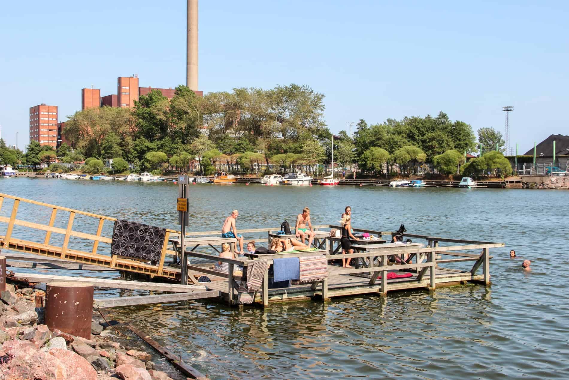 A group of people bathing and rugs drying on a jetty in the waterside area of Merihaka in Helsinki.