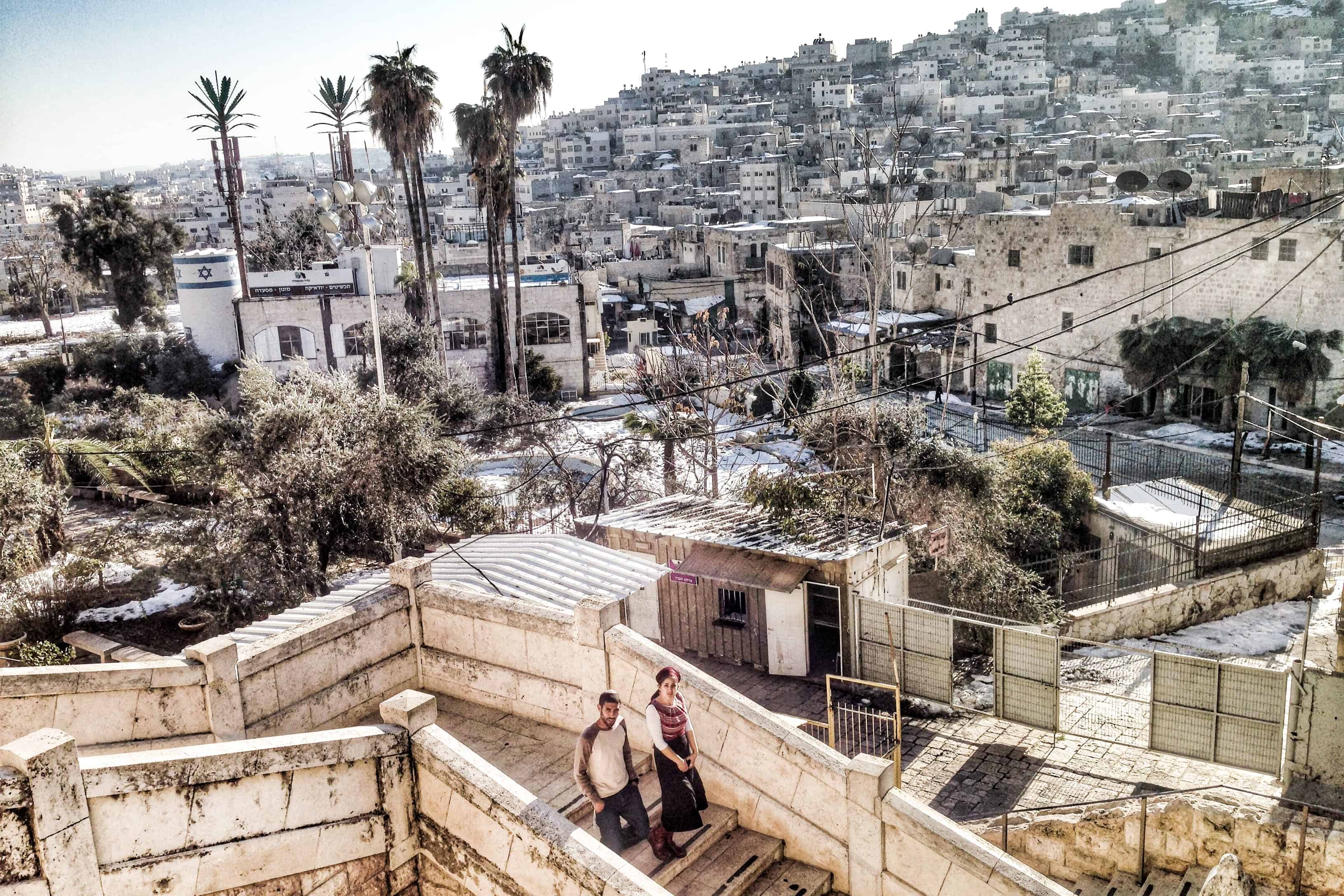 A man and woman walking down white stone steps in a built-up residential area of the city of Hebron in the West Bank, Palestine