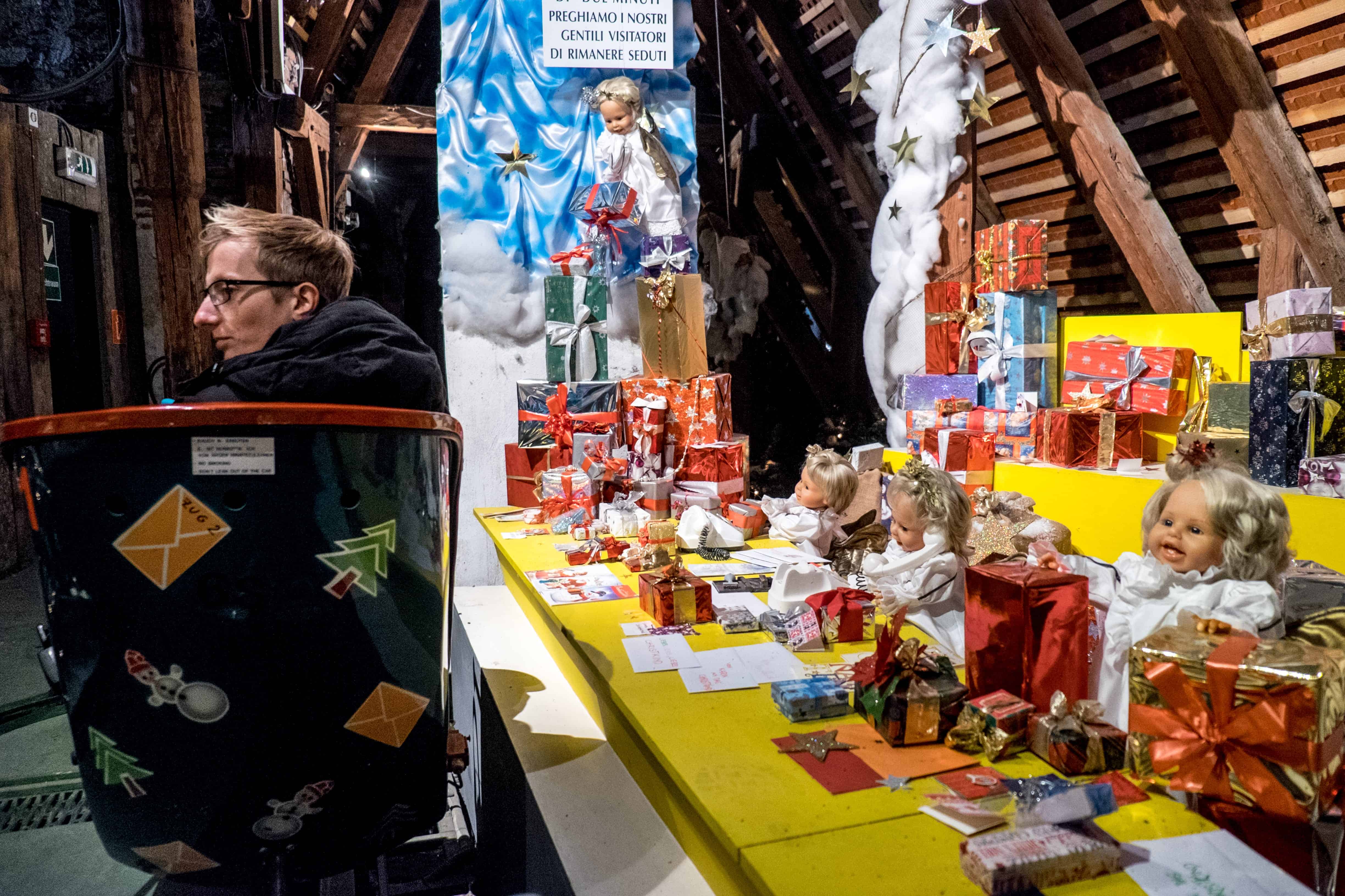 A man rides the Steyr Christmas Museum Train in Austria past a display of angel dolls and presents.