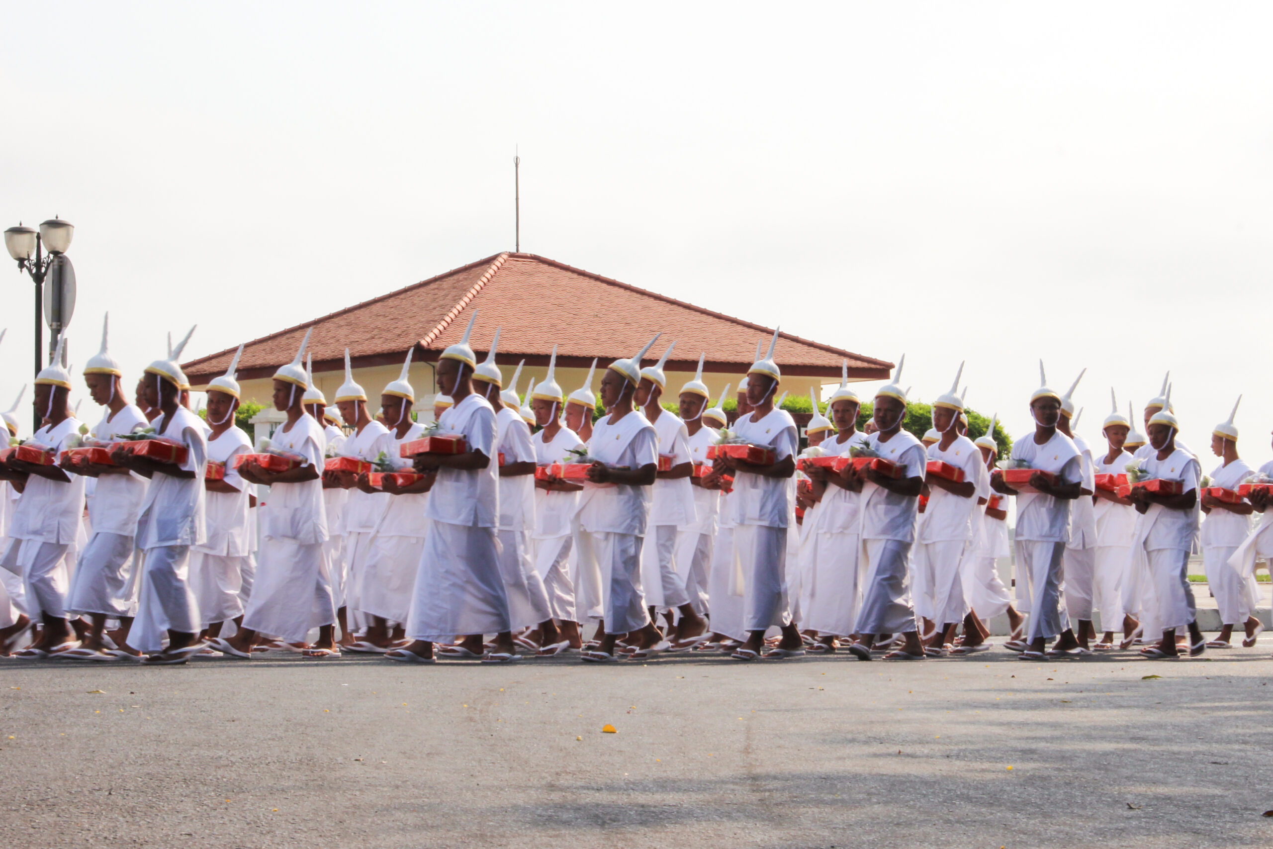 Men in white dress and the pointed noble Lomphok hat participating in the royal funeral procession for the late King Norodom Sihanouk of Cambodia.