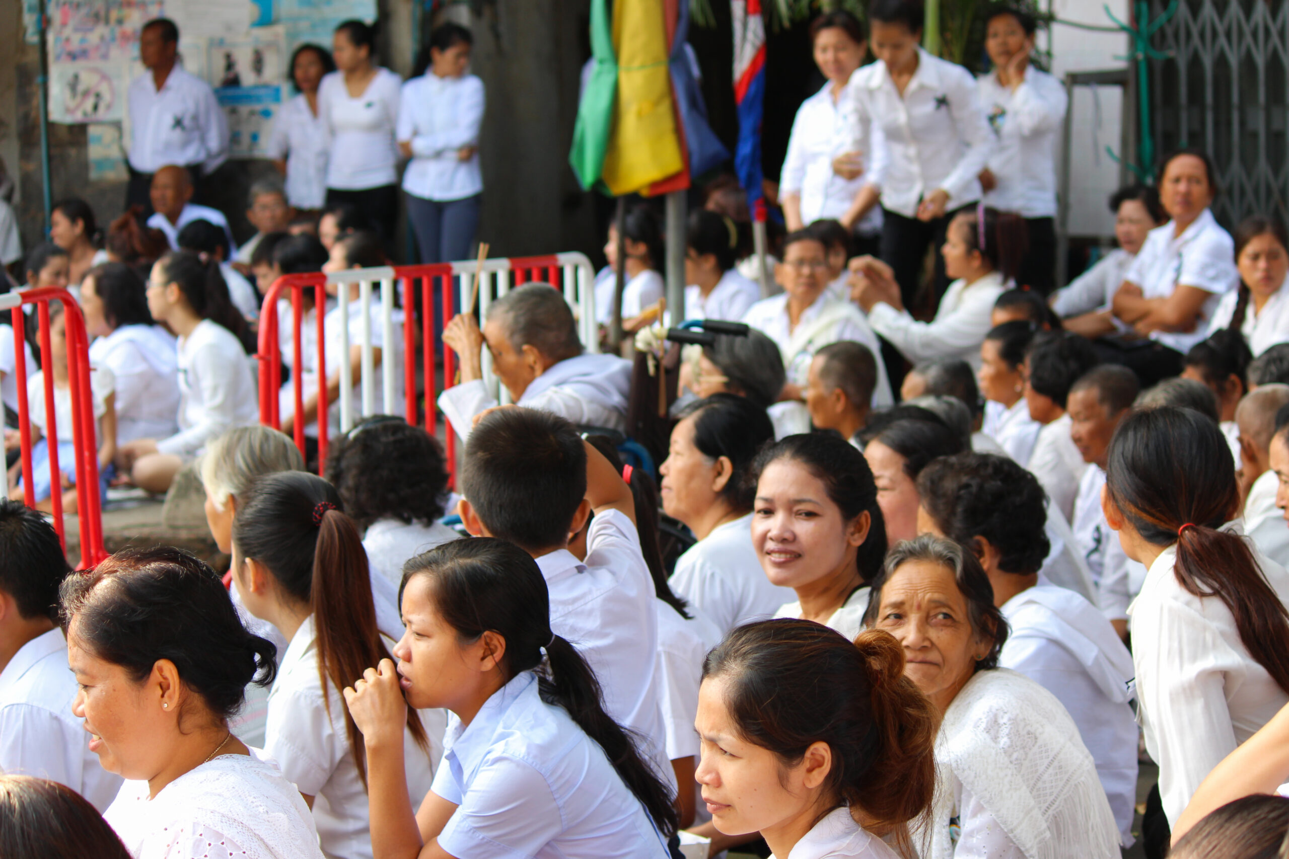 A group of Cambodian mourners dressed in black and white sit on the floor awaiting the parade of the state funeral of Norodom Sihanouk.