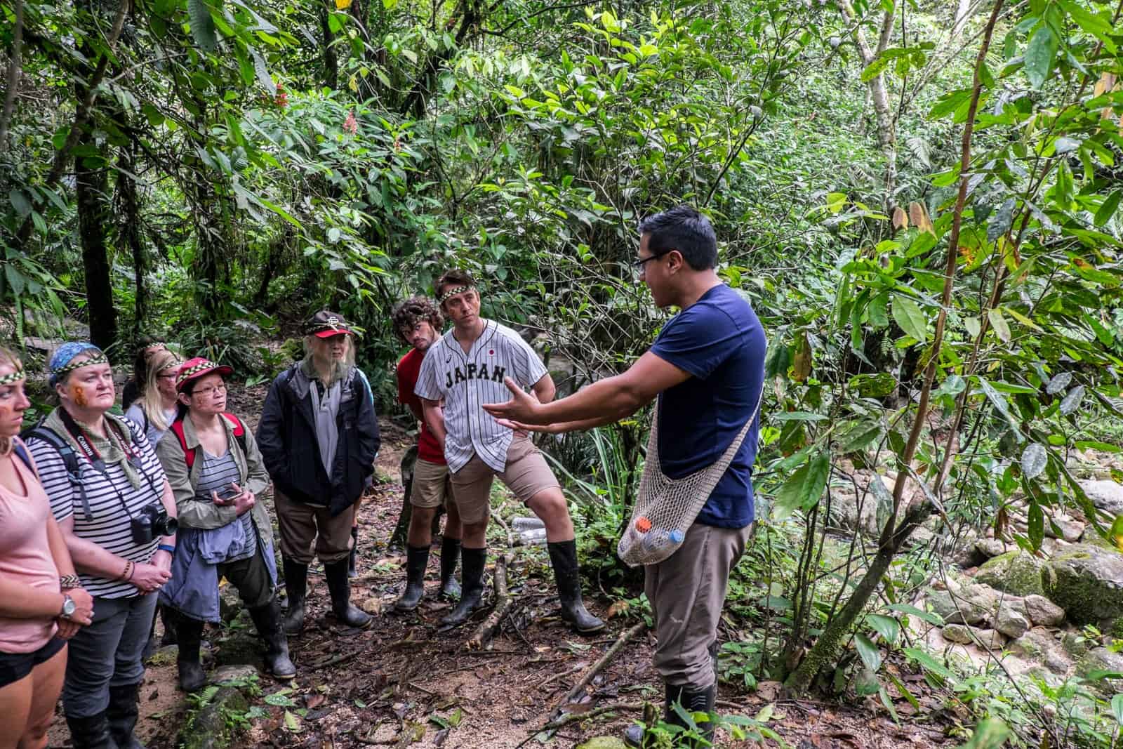 A man in a blue t-shirt leads a small group on a jungle tour in the Ecuador Amazon. 