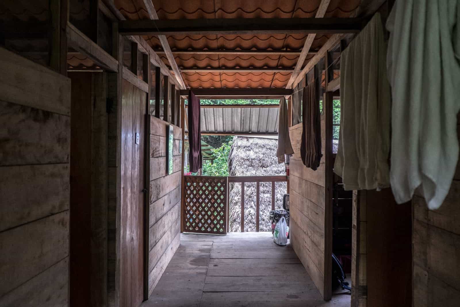 The hallway of a wooden hut with open bedroom doors - a typical lodge in the Ecuador Amazon. 