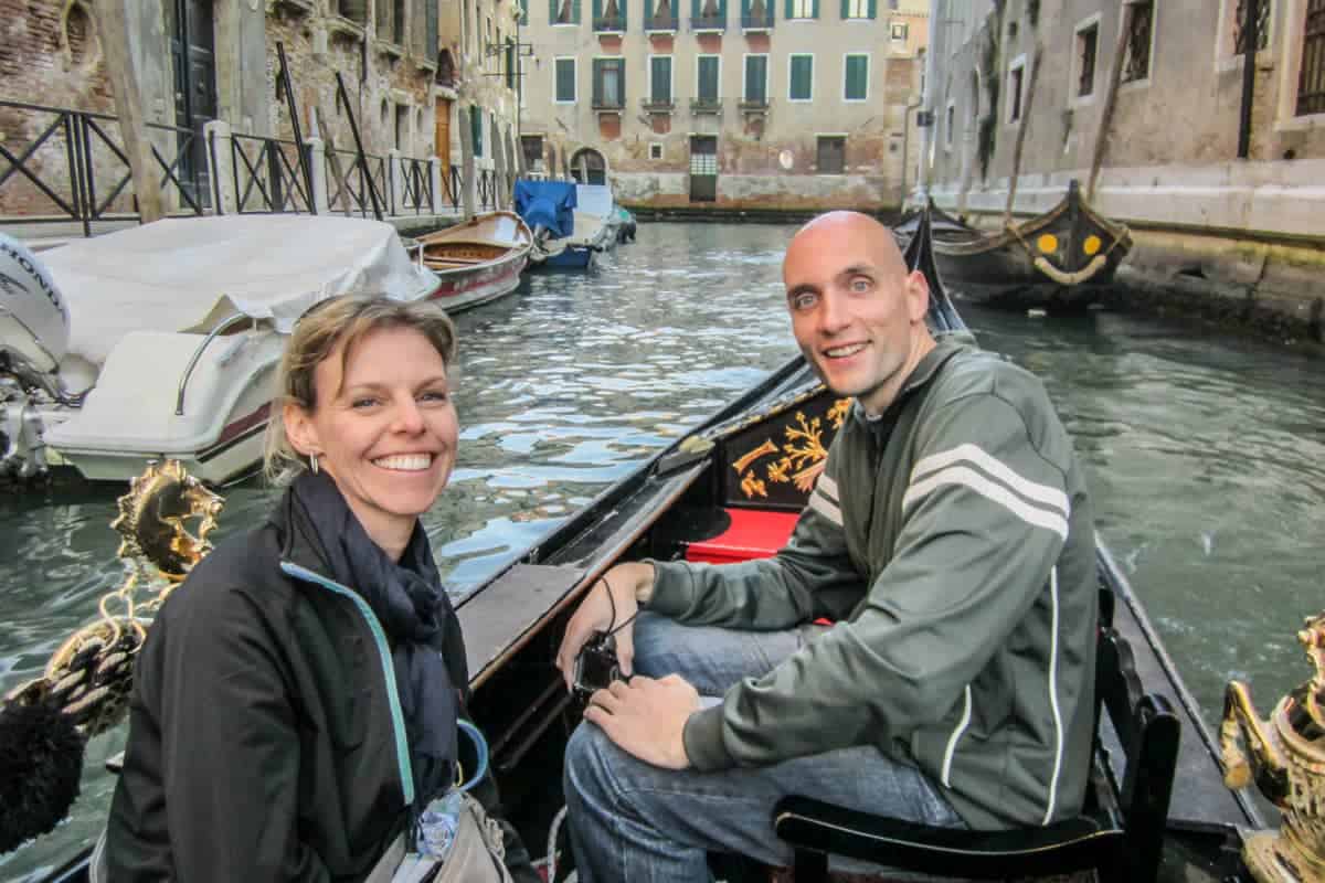 Two tourists on a gondola ride in Venice floating down one of the smaller canals