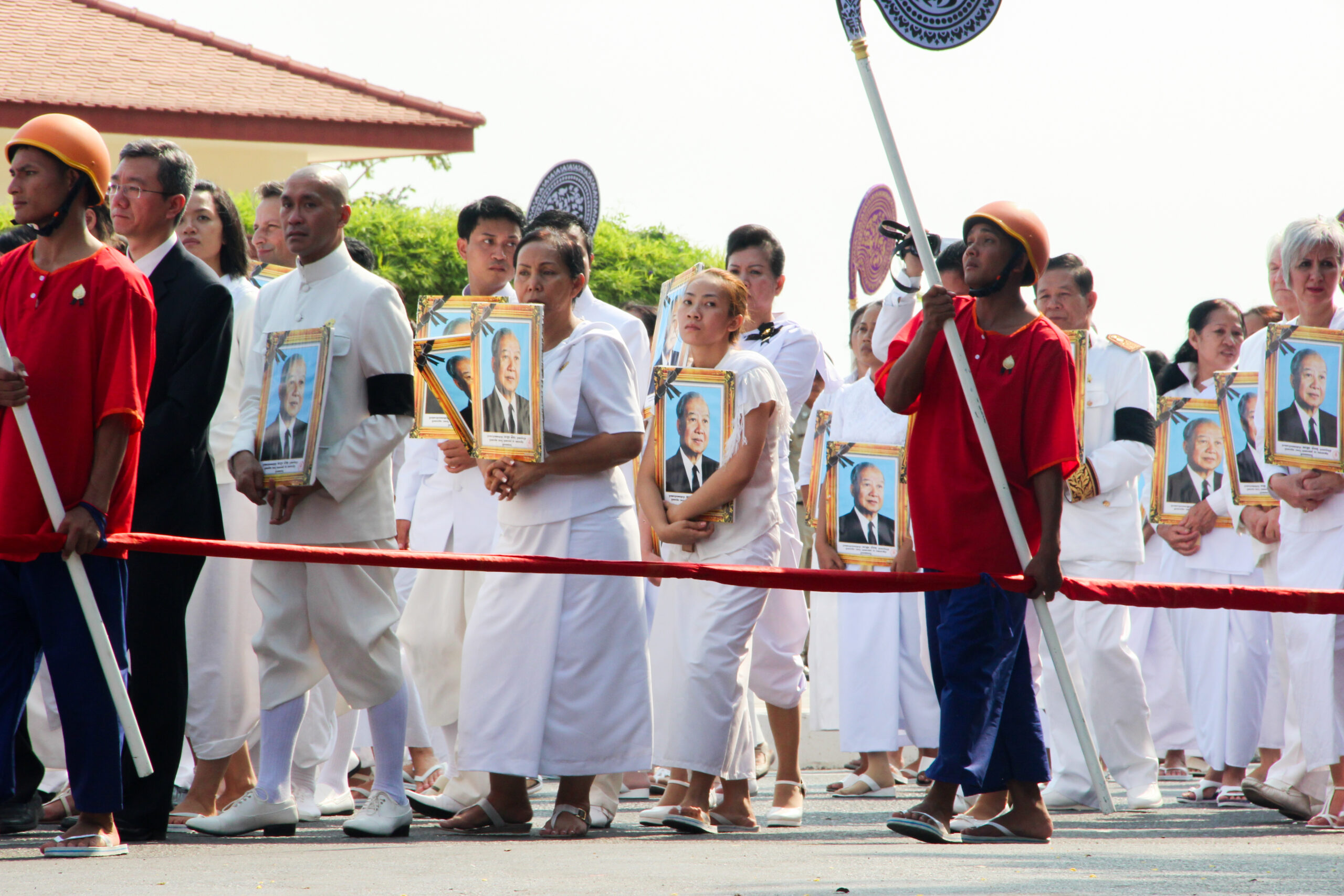 Parade mourners dressed in white carrying a golden framed image of Norodom Sihanouk, King of Cambodia.
