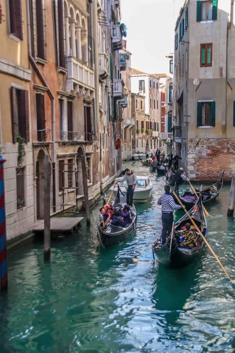 Tourists riding in Gondolas and passing one another on a narrow canal in Venice